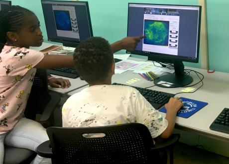 Two students working on computer with an astronomical image