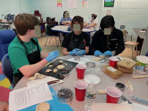 Two mentors and one mentee sculpt clay objects