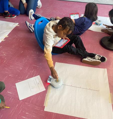 Black elementary school student solving math problem with Finch robot